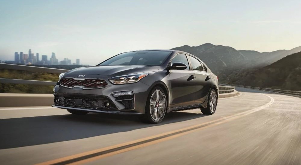 A grey  2020 Kia Forte GT is shown driving past a city after visiting a used Kia dealer.